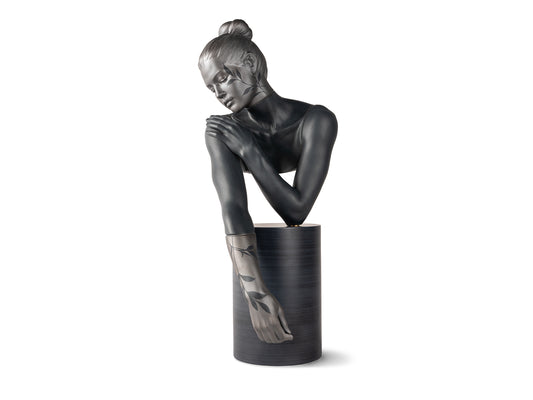 A bust of a woman on a cylinder who is leaning on her elbow. The piece is made of dark grey porcelain with matte and metallic finishes with leaves painted across her face and one arm