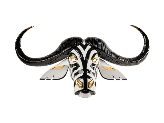 A mask in the shape of a buffalo head with long black horns. The face is made with striped black and white porcelain and the features are decorated with gold lustre