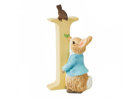 A pastel yellow letter I with a small brown rabbit figure offering some leaves to a brown bird that is perched on top of the I