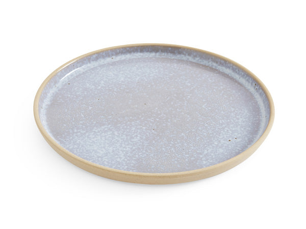 A stoneware coupe-style dinner plate with raised edges. Textured exterior in a neutral warm stone colour, the plate's interior showcases a pale blue reactive glaze reminiscent of aquamarine hues.