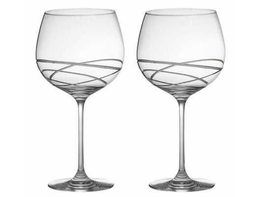 A pair of crystal gin balloons with a swirling orbital pattern cut around the base of each