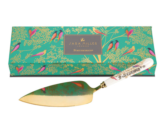 A gold cake slice with a white porcelain handle, decorated with gold leaves and brightly coloured birds.