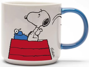 The mug features a drawing of Snoopy perched on his iconic red-roofed house, pondering over his writing with a typewriter, while tossing a crumpled paper. The back of the mug boldly declares 'Genius at Work' 