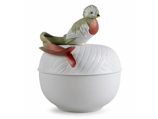 A ribbed matte white porcelain box with a bright green and red tropical bird perched on the lid.