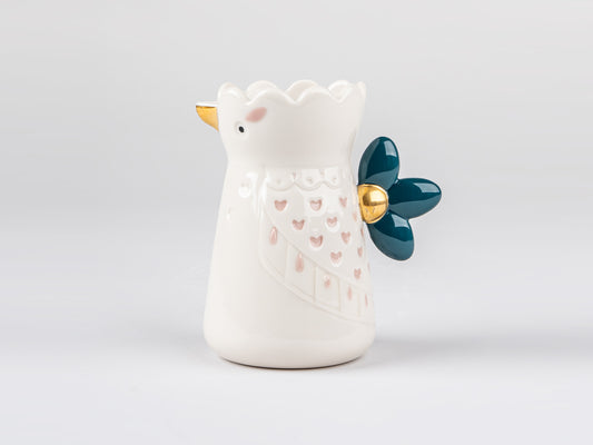 A small white cream jug that is designed to look like a bird with pink hearts acting as wing feather details. It has a blue handle at the back that looks like a tail