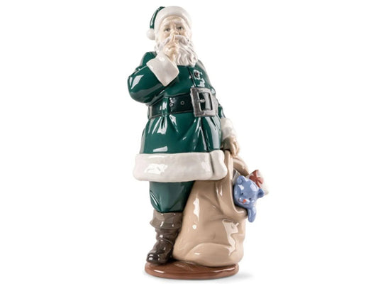 This glazed porcelain Santa Claus invites us to safeguard his secret as he embarks on his gift-giving mission. This figurine is remarkable for its emotive portrayal, endearing charm, and the wealth of intricate details. These details encompass his iconic attire and the overflowing sack of toys intended for children. Santa's costume is adorned in a rich, holiday-inspired deep green, a colour widely associated with the festive season.