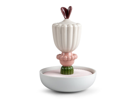 A porcelain perfume diffuser with a small bowl at the base, filled with porous pink porcelain, topped with an abstract flower