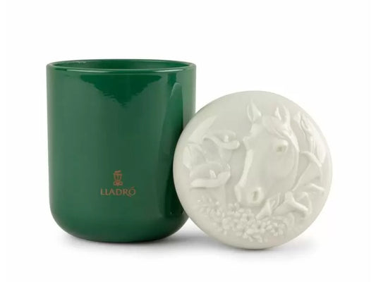An emerald green glass candle with a white porcelain lid that is engraved with a horse head design