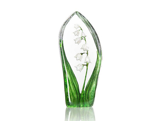 A crystal ornament featuring a lily of the valley design, which has large green leaves on either side of the piece and a slender stem with small white bell-shaped flowers on it in the centre