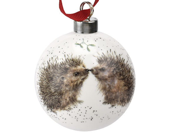 A white bauble with kissing hedgehogs on it, hung on a red ribbon