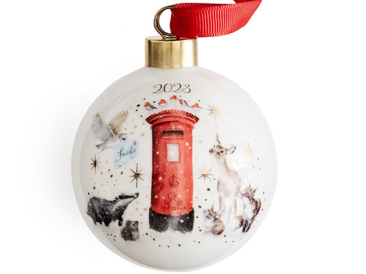 A white porcelain bauble adorned with 22-carat gold speckles, arranged in delicate dots and stars across its surface. The bauble showcases a watercolour illustration of woodland animals, each gazing expectantly at a vibrant red post box. The charming scene features adorable red-breasted robins perched atop the post box, accompanied by a delightful ensemble of a deer, fox, rabbit, hedgehog, badger, and barn owl, with the latter holding an envelope addressed to Santa.