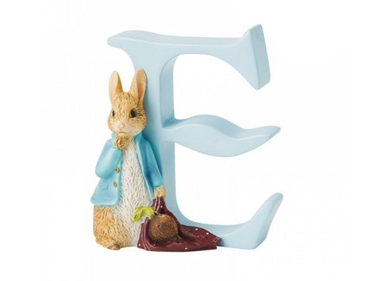 A blue letter E with a statue of Peter Rabbit in front, wearing a blue jacket and carrying a red handkerchief and an onion