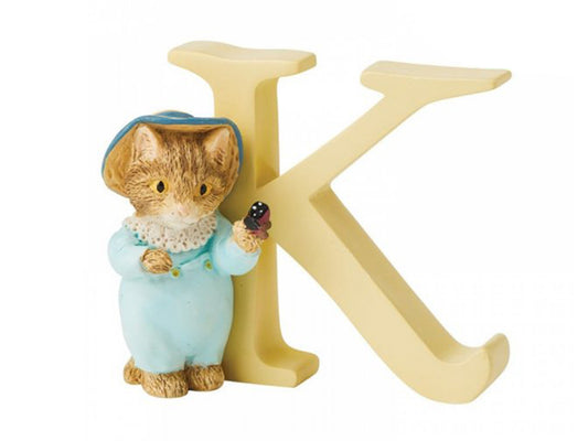 A yellow capital letter 'k' with a kitten figure standing to the left, dressed in a blue onesie and wearing a straw hat with a butterfly perched on its paw
