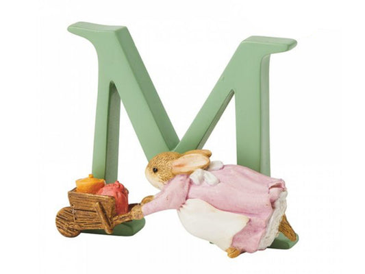 A sage green capital letter M with a small brown bunny in a purple dress pushing a wheelbarrow full of food in front of it