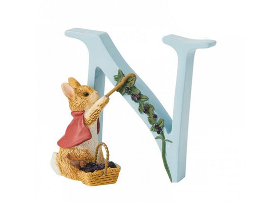 A pastel blue letter N with a small brown rabbit picking blackberries off a stem that grows up the diagonal beam of the N. The rabbit is wearing a red cape and has a basket at her feet full of blackberries.