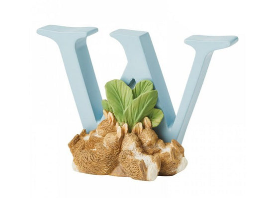 A pastel blue capital W with four bunnies sleeping against a turnip in front of it
