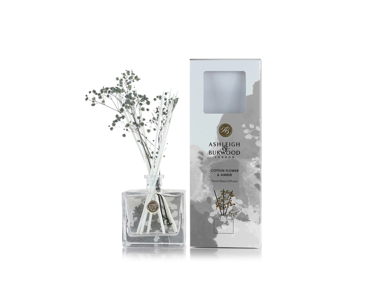 A beautiful glass diffuser bottle with white reeds and dried gypsophila flowers with a grey and white gift box and a cotton flower and amber scent