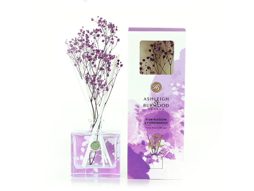 A glass bottle reed diffuser with white reeds and purple dried gypsophila in a marbled watercolour box.