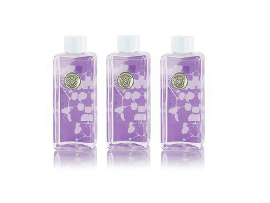Three bottles of reed diffuser liquid with a purple and white floral background and white lids