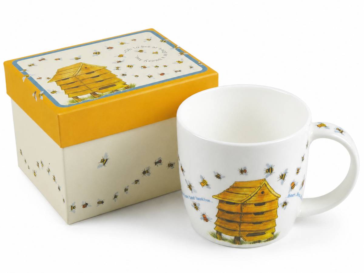 A white ceramic mug with a yellow and brown beehive illustration and small bee motifs, shown next to its matching gift box with a yellow lid and cream body.