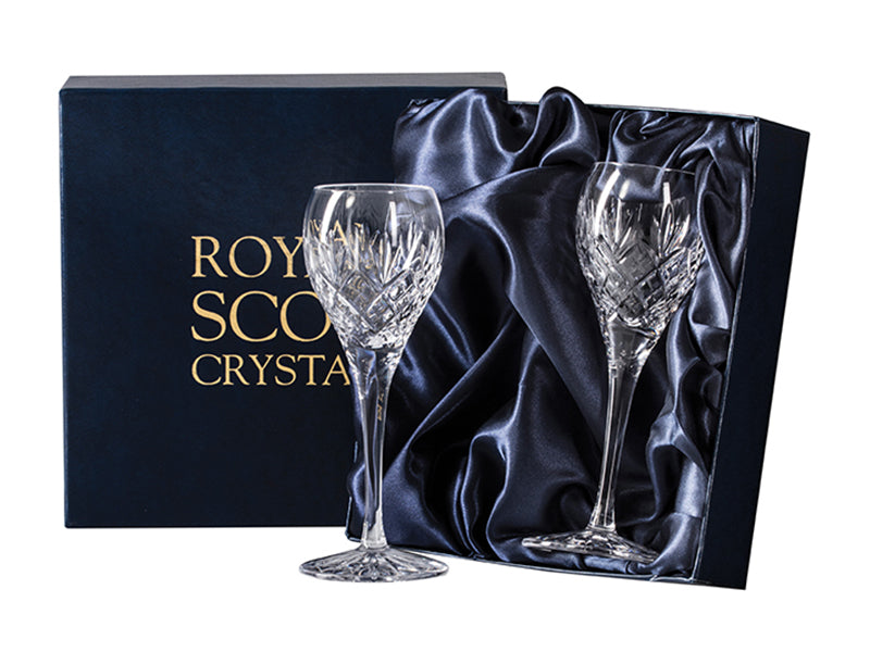 A pair of stemmed port and sherry glasses in a navy blue presentation box with gold branding on the lid. Each glass is engraved with a bed of diamonds at the base of the bowl, with a triple-flicked fan on top.