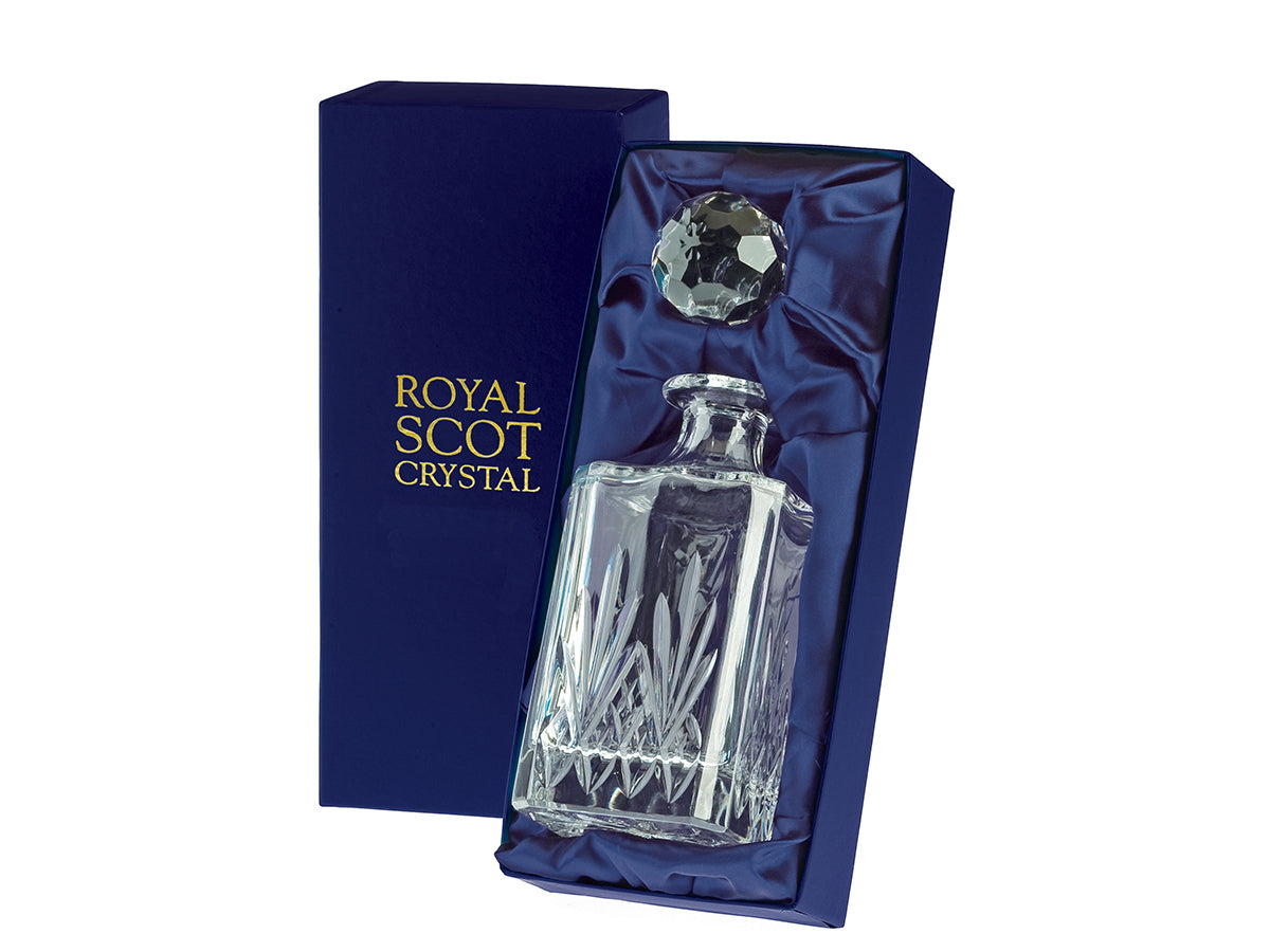 A square spirit decanter with a highland cut, which consists of diamonds around the base and five-pointed fan reaching up towards the smooth neck, with a golf-ball style stopper. It comes in a navy-blue silk-lined presentation box with gold branding on the lid.