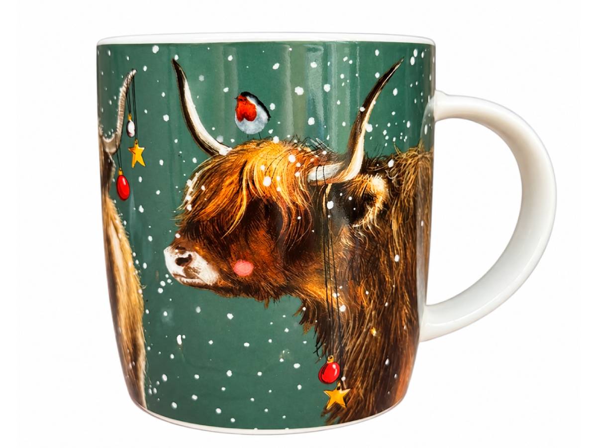 A white ceramic mug featuring a festive winter illustration of a shaggy Highland cow with red accents, a robin bird, and snowflakes on a dark green background.
