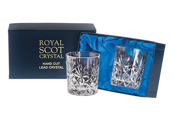 A pair of large whisky tumblers with a kintyre cut, which is made up of a base of diamonds with a seven-pointed fan sitting above them. The tumblers have a smooth rim. They come in a navy-blue silk-lined presentation box with gold branding on the lid.