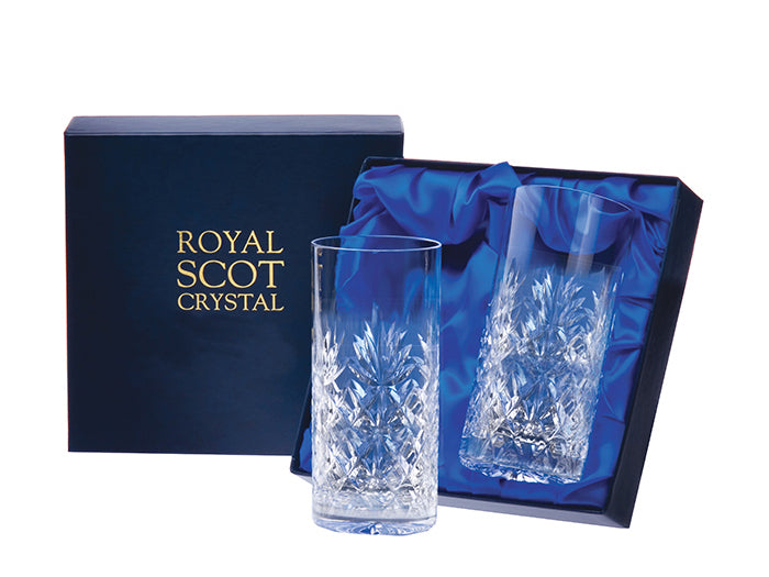 A pair of tall crystal highball tumblers with a series of diamonds cut around the base, topped with a seven-pointed fan and a smooth rim. They come in a navy-blue silk-lined presentation box with gold branding on the lid.