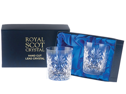 A pair of small whisky tumblers with a bed of diamonds cut around the base, topped with a seven-pointed fan and a smooth rim. They come in a navy-blue silk-lined presentation box with gold branding on the lid.