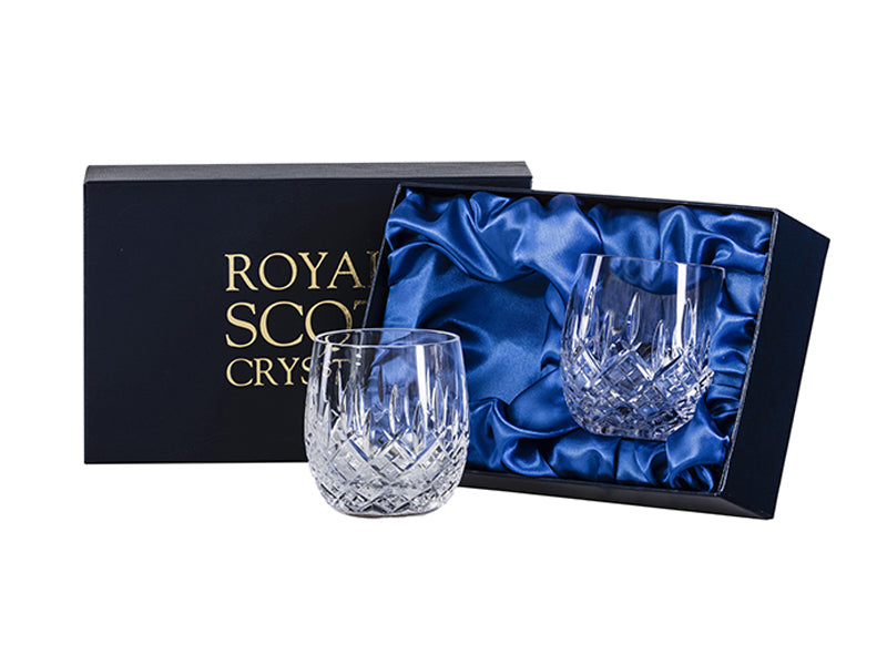 A pair of crystal glasses with a bed of diamonds and individual dashes reaching up towards the rim, all cut into the exterior of the tumblers. They come in a navy blue silk-lined presentation box with Royal Scot branding on the lid, embossed with gold
