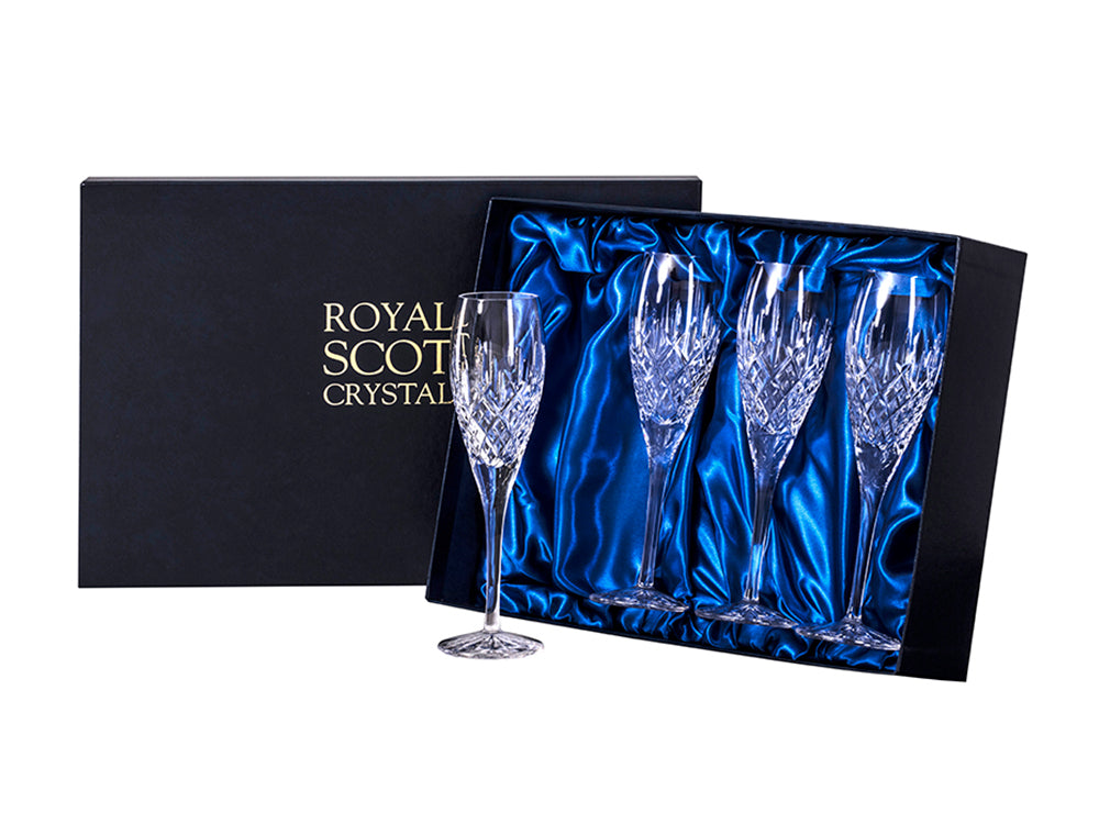 A set of four matching champagne flutes engraved with the classic London design which has a bed of diamonds at the base of the flute and single flicks reaching up towards the smooth rim. They come in a navy blue presentation box with gold branding on the lid.