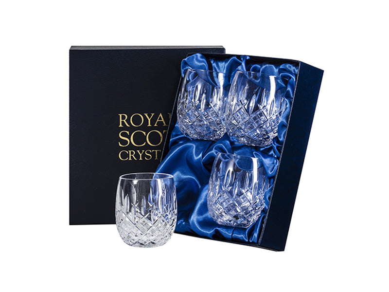 A set of four rounded gin and tonic tumblers, featuring a cut design with a bed of diamonds at the base and single dashes reaching up towards the smooth rim. They come in a navy blue silk-lined presentation box with Royal Scot branding embossed in gold on the lid