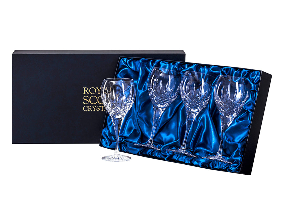 A set of four large wine glasses, each hand-cut with a bed of diamonds at the base of the bowl, with single flicks reaching up towards the smooth rim. They come in a navy blue silk-lined presentation box, with gold branding on the lid.
