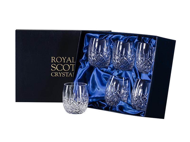 A set of six large gin and tonic tumblers with a cut pattern on the outside that features a bed of diamonds around the base, topped with single flicks going towards the smooth rim. They come in a navy-blue silk-lined presentation box with gold branding on the lid.