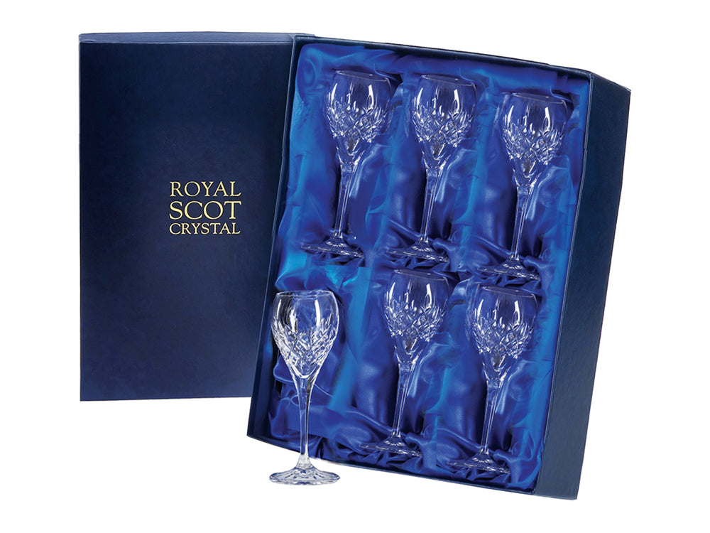 A set of six stemmed crystal port glasses with a cut design on the outside of the bowl. The pattern features a bed of diamonds around the bottom, topped with single flicks that reach up towards the smooth rim. They come in a navy-blue silk-lined presentation box with gold branding on the lid.