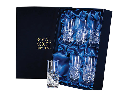 A set of six crystal highball tumblers with a cut design on the outside. The cut pattern has a bed of diamonds around the base, topped with single flicks going up towards the smooth rim. They come in a navy-blue silk-lined presentation box with gold branding on the lid.