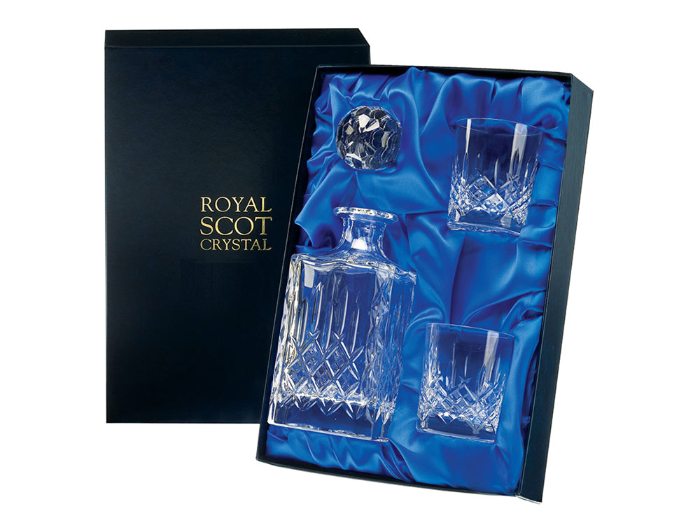 A whisky set comprised of a square spirit decanter and two matching whisky tumblers. They are all cut with a London design made up of a bed of diamonds and single flicks going up towards the smooth tops of each piece. They come in a navy blue silk-lined presentation box.