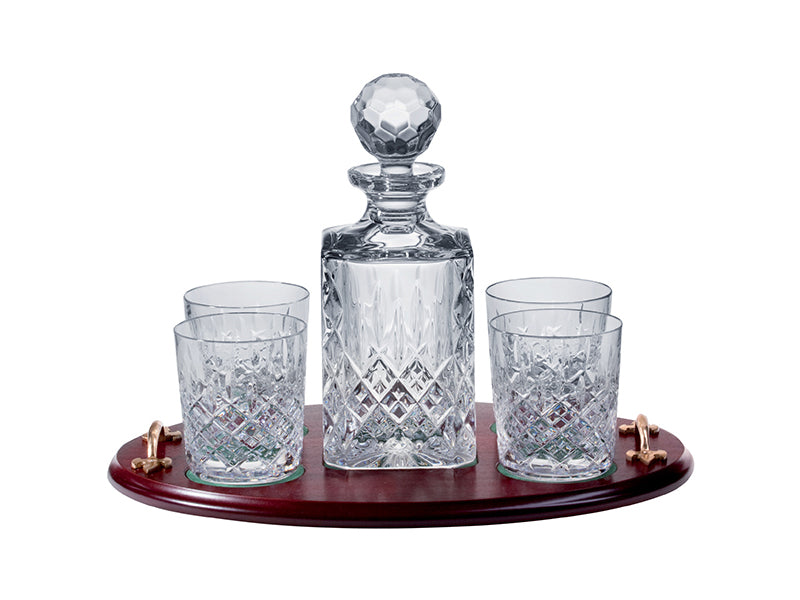 A crystal decanter and four matching glasses with an intricate cut pattern on the outside, resting on a solid oak tray with gold handles