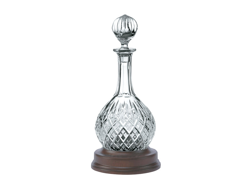 A crystal decanter with a round bottom and long neck, sitting on a mahogany base