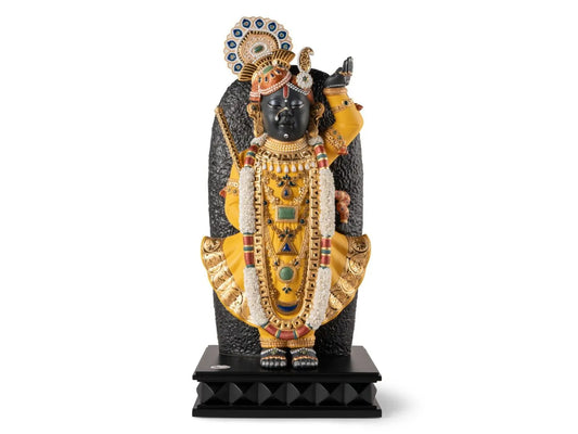 A statue of Lord Shrinathji on a black base and background, made with ornate clothing and floral details