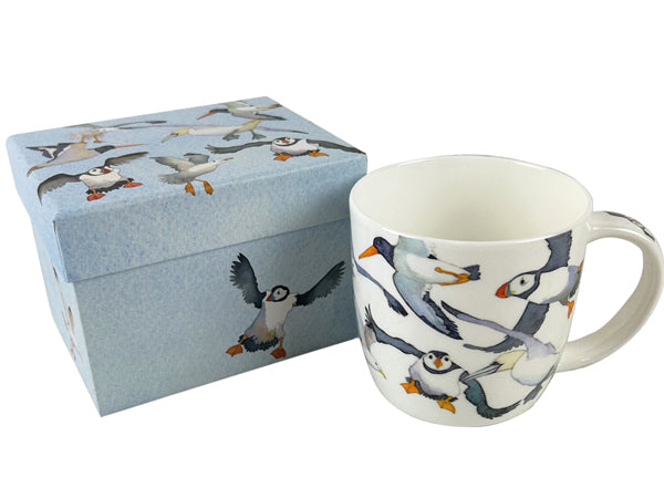 A white ceramic mug and matching gift box featuring a whimsical puffin illustration pattern, set against a plain white background.