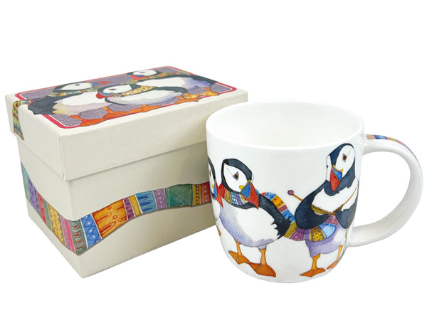 A white ceramic mug and matching gift box featuring a colorful illustration of puffins wearing patterned clothing, photographed on a plain white background.