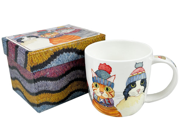 A white ceramic mug with illustrated cats wearing knit hats, shown next to a matching patterned gift box on a white background.