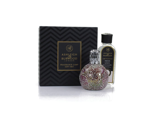 A pink-toned mosaic style fragrance lamp with a silver top and a bottle of fresh linen scented lamp liquid in a black and gold gift box