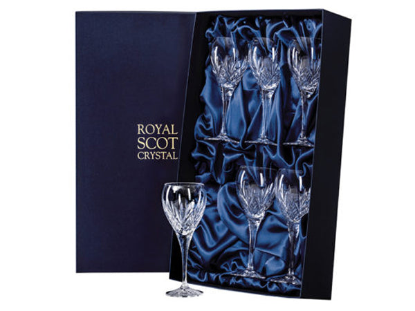 A set of six matching port glasses with small bowls and slender stems, with a highland cut consisting of diamonds around the base of the bowl and a five-pointed fan reaching up towards the smooth rim. they come in a navy-blue silk-lined presentation box with gold branding on the lid.