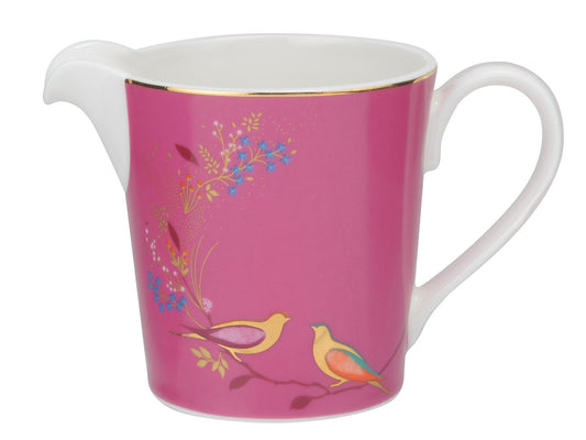 A white porcelain cream jug with a bright pink transfer, featuring gold details on delicate flowers, leaves and birds