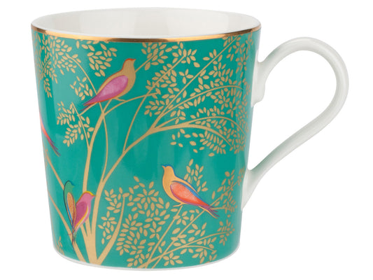 A bright green mug with intricate gold leaf pattern and jewel toned birds