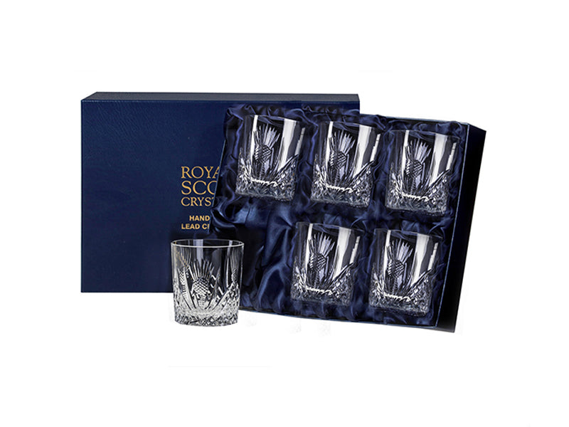A set of six matching whisky tumblers with a scottish thistle cut into the exterior of each. They come in a navy-blue silk-lined presentation box with gold branding on the lid.