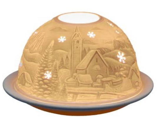 A dome-shaped decorative lamp or cover with an embossed winter village scene, shown illuminated against a plain white background.